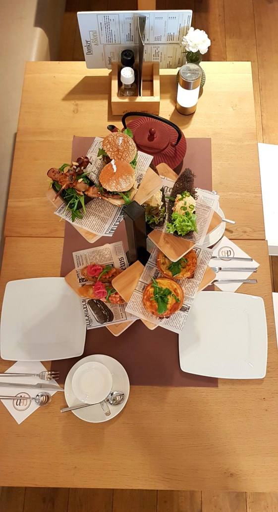 Een gedekte tafel bij Donker & Blond met broodjes, koffie en servies, van bovenaf